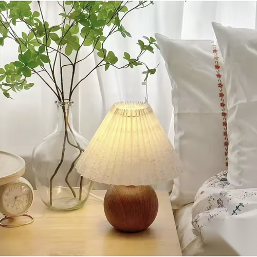 Lampe à poser boule effet bois avec abat-jour plissé sur une table de chevet