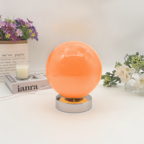 Lampe à poser boule en verre orange allumée