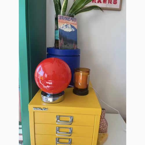 Lampe à poser boule en verre orange sur un meuble, photo client