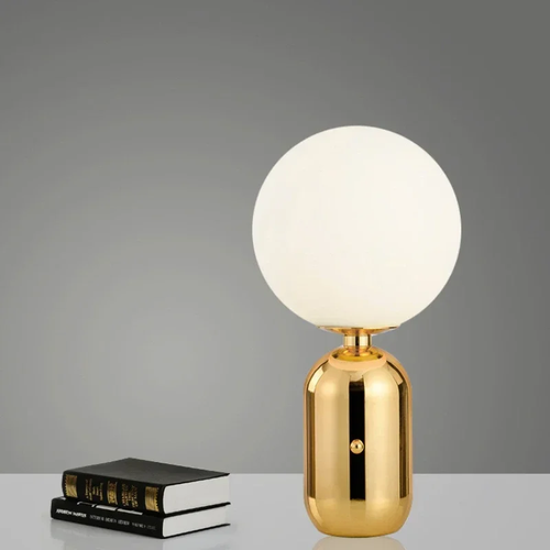 Lampe à poser boule opaline pied doré sur un bureau
