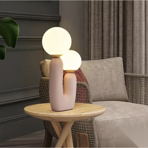 Lampe à poser double boule en verre, pied arche rose sur un guéridon