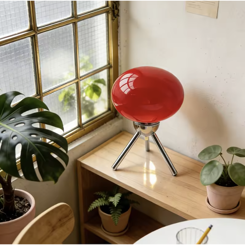 Petite lampe tripode abat-jour en verre orange allumée
